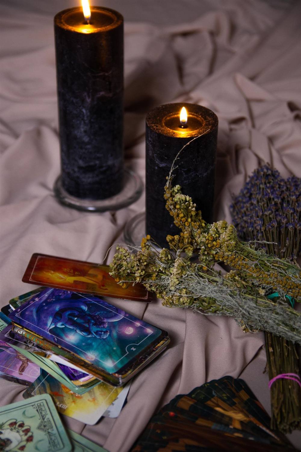 Velas negras con tarot, lavanda y piedras sobre tela oscura
