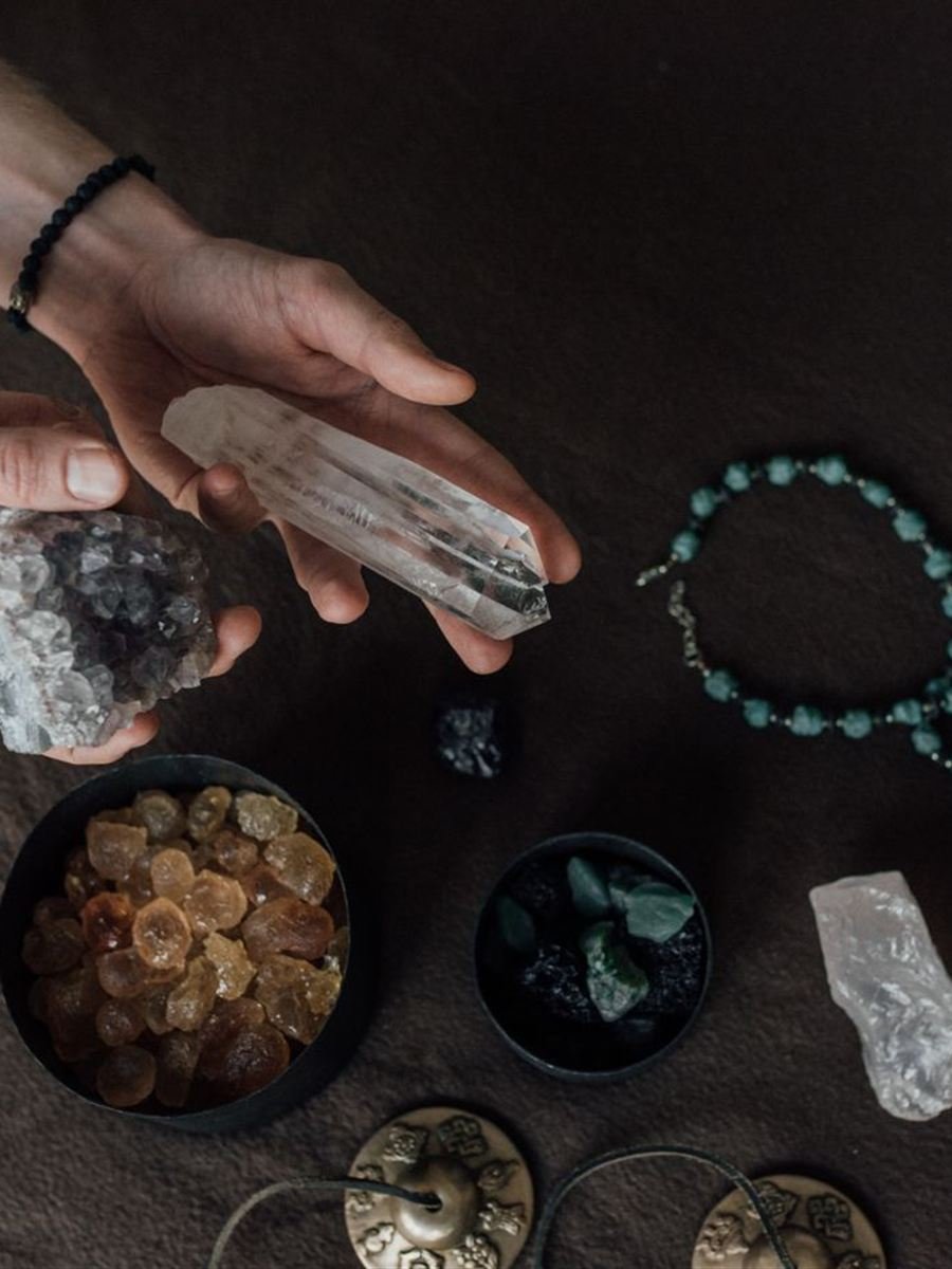 Manos sosteniendo cuarzos y piedras sobre una mesa oscura