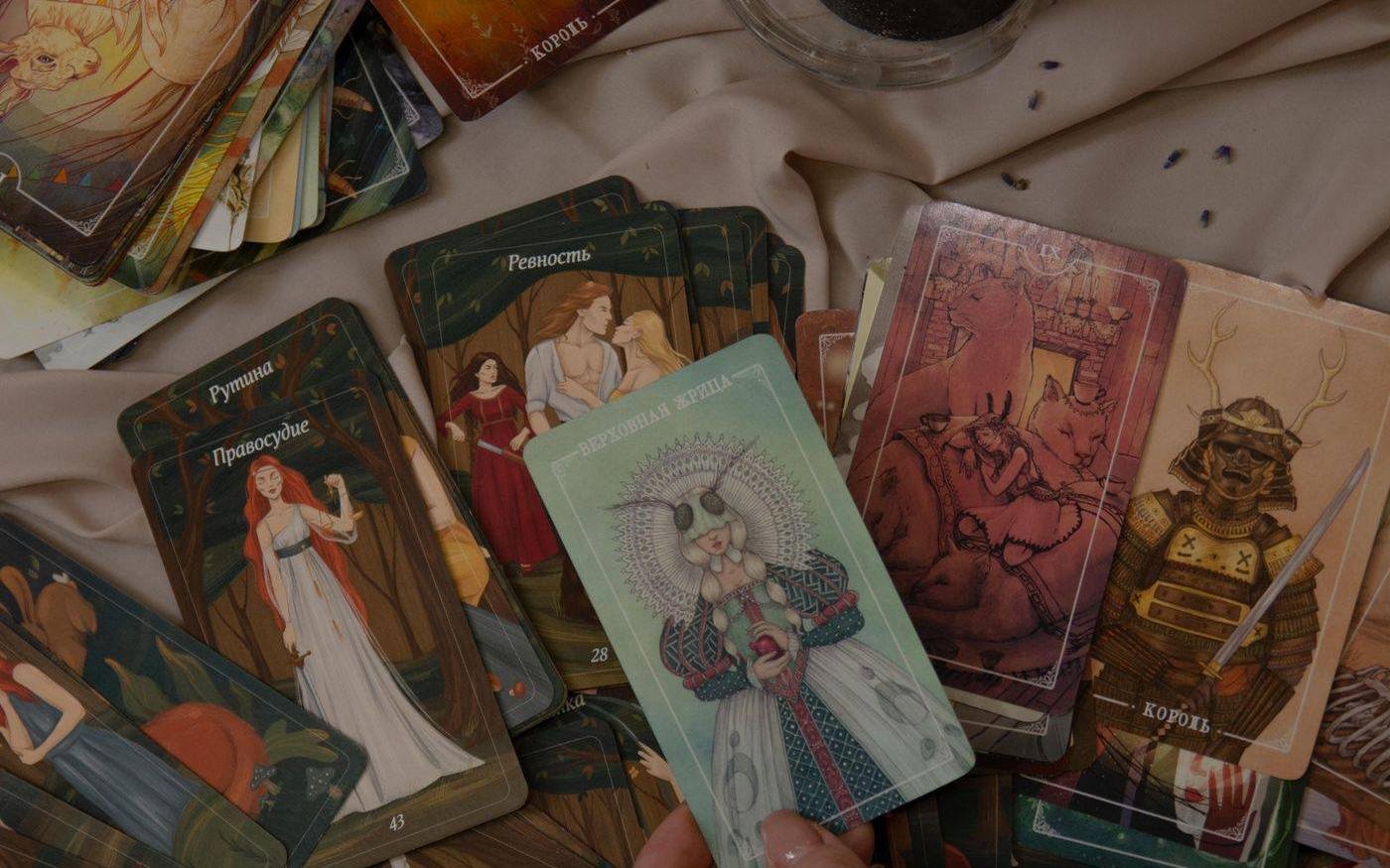Manos leyendo cartas de tarot junto a velas y objetos rituales sobre tela